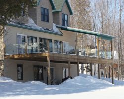 This picture is the clean look of no top or bottom rail. Our customer wanted minimal obstruction of their Lake Charlevoix view. 1/2" clear tempered installed into dado wood posts.